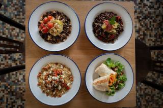 Quatre bols de salades de lentilles, de pois chiches et de céréales vus de dessus sur une planche en bois